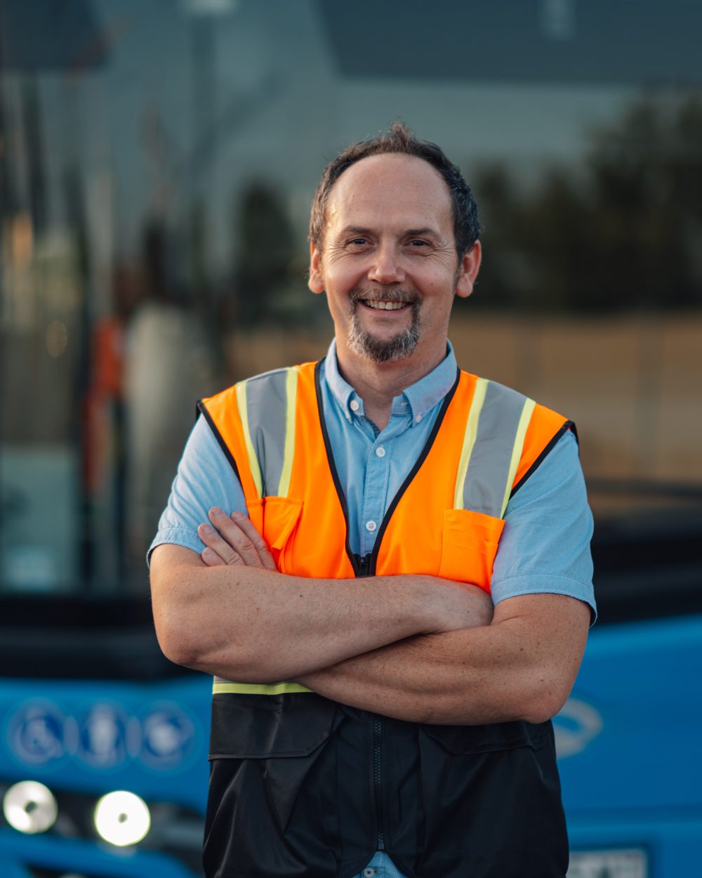 Busfahrer in Warnweste vor seinem Omnibus